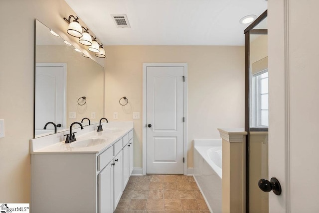 full bathroom with double vanity, visible vents, a sink, and a garden tub