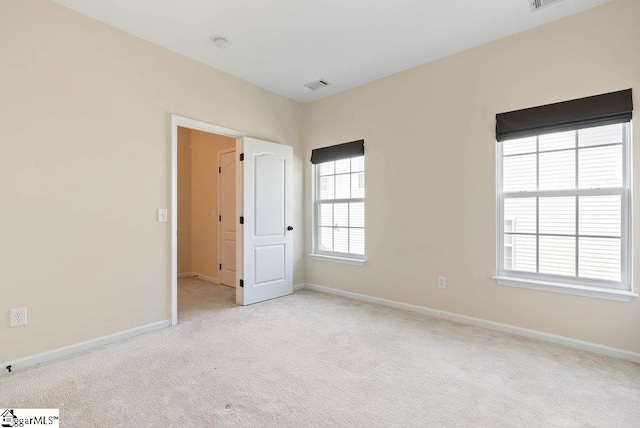 unfurnished room with light colored carpet, baseboards, and visible vents