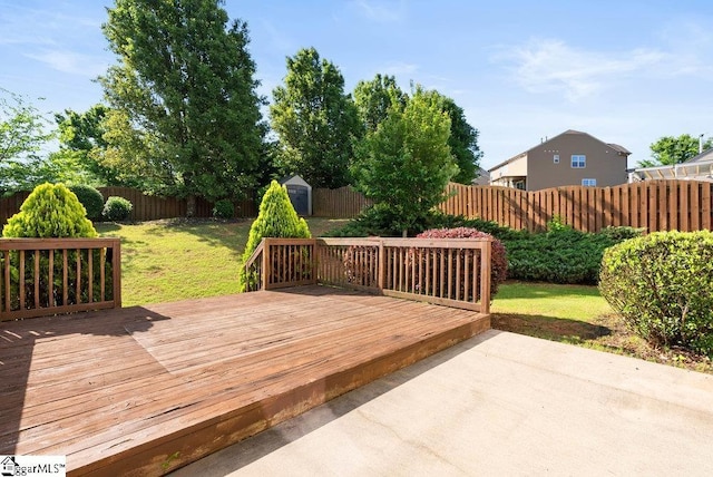 deck featuring a storage unit, a fenced backyard, an outbuilding, a patio area, and a lawn