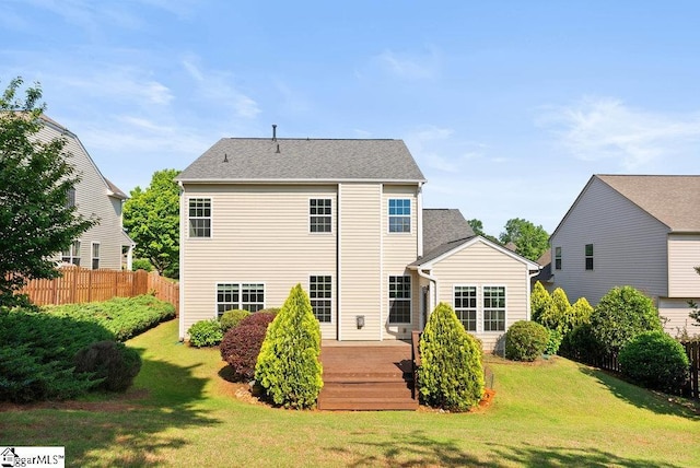 rear view of property featuring fence, a yard, and a wooden deck