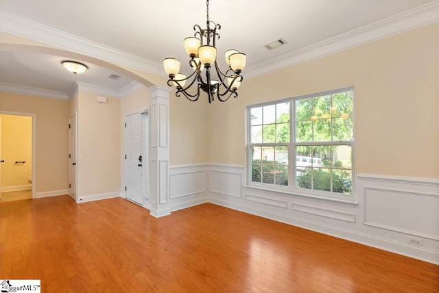 empty room with visible vents, arched walkways, a chandelier, and light wood-type flooring