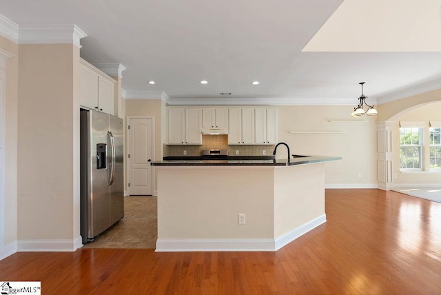 kitchen featuring dark countertops, an inviting chandelier, light wood-style flooring, stainless steel appliances, and decorative backsplash