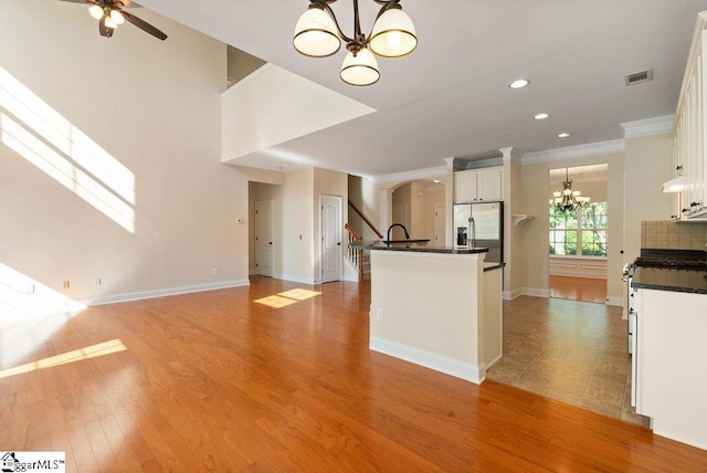 kitchen with visible vents, ornamental molding, dark countertops, stainless steel fridge, and white cabinets