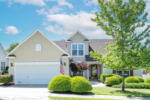 view of front of home featuring an attached garage, driveway, and a shingled roof