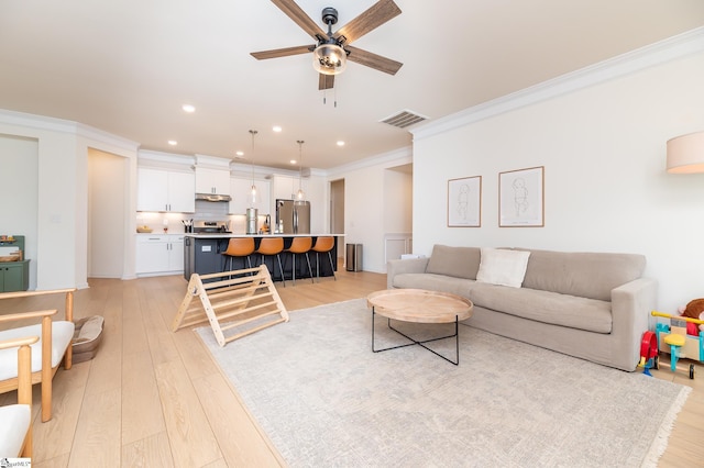 living room featuring a ceiling fan, visible vents, light wood-type flooring, ornamental molding, and recessed lighting