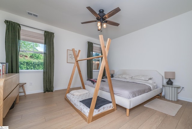 bedroom featuring ceiling fan, baseboards, visible vents, and wood finished floors