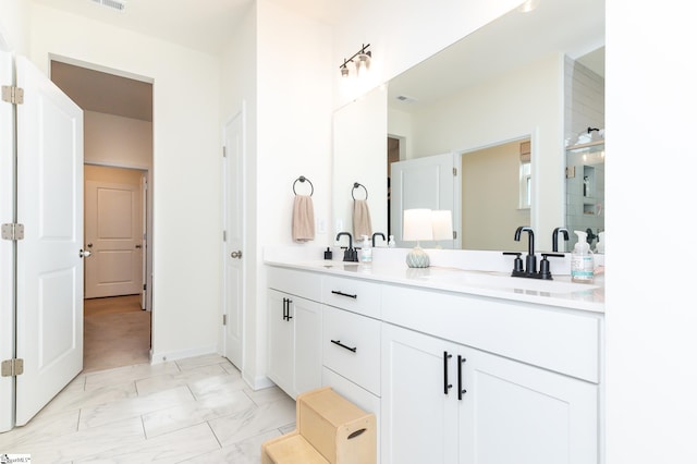 full bath with double vanity, a sink, marble finish floor, and baseboards