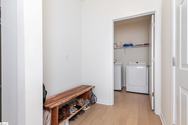 clothes washing area with independent washer and dryer, baseboards, laundry area, and light wood-style floors