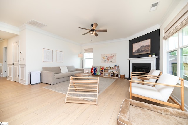 living room featuring ornamental molding, a ceiling fan, light wood-type flooring, and visible vents