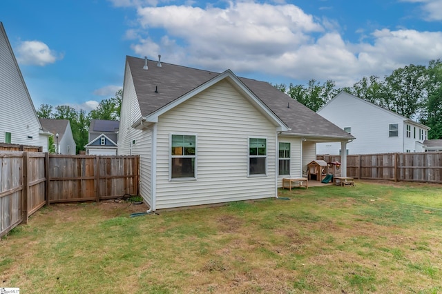 rear view of house featuring a fenced backyard, a shingled roof, and a yard
