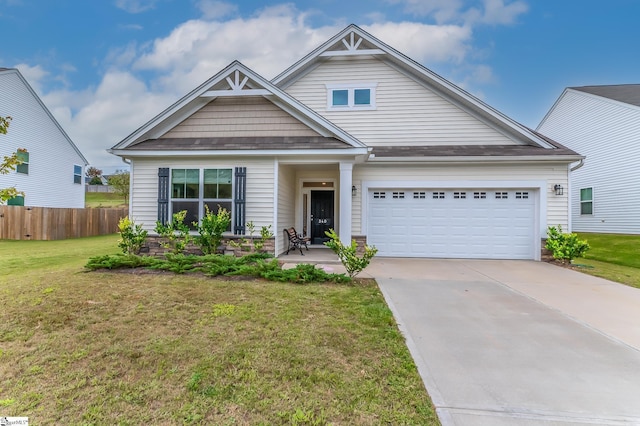 craftsman-style home featuring fence, concrete driveway, a front lawn, and a garage
