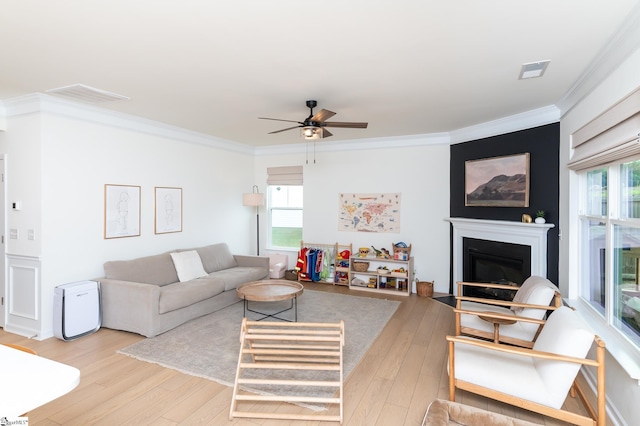 living room featuring visible vents, a ceiling fan, light wood-style flooring, and crown molding