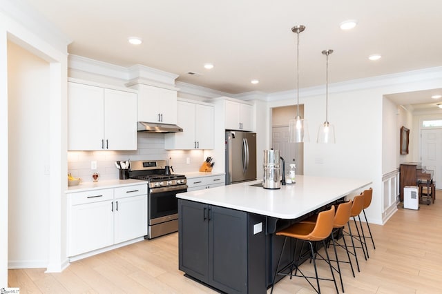 kitchen featuring light wood-style flooring, under cabinet range hood, white cabinets, and stainless steel appliances
