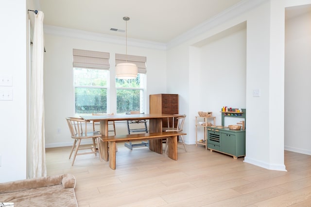 interior space featuring crown molding, baseboards, light wood finished floors, and visible vents