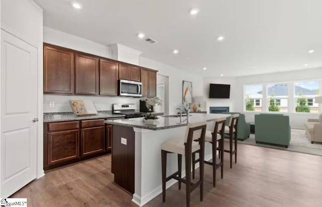 kitchen featuring visible vents, open floor plan, light wood-style flooring, and stainless steel appliances