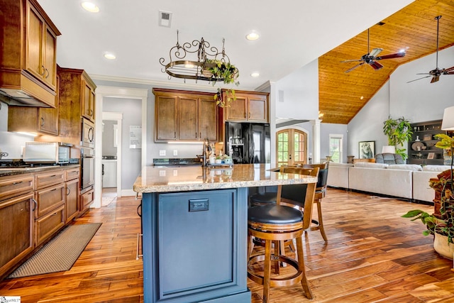kitchen with visible vents, an island with sink, ceiling fan, light wood finished floors, and appliances with stainless steel finishes