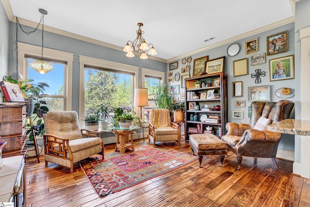 sitting room with crown molding, a chandelier, visible vents, and hardwood / wood-style floors