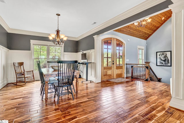 dining space with a notable chandelier, arched walkways, french doors, light wood-type flooring, and visible vents