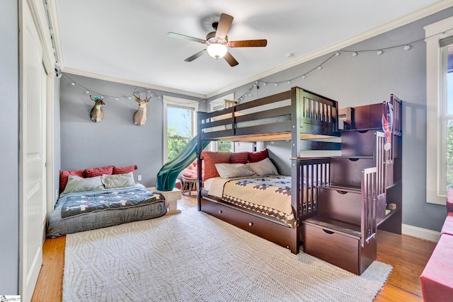 bedroom with crown molding, a ceiling fan, baseboards, and wood finished floors
