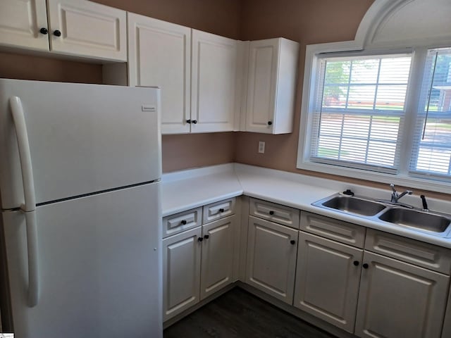 kitchen featuring freestanding refrigerator, a sink, healthy amount of natural light, and white cabinetry