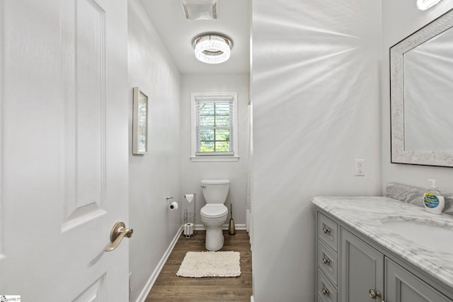 bathroom with vanity, baseboards, wood finished floors, and toilet