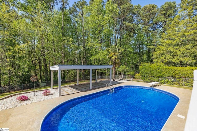 view of pool featuring a fenced in pool, fence, and a diving board