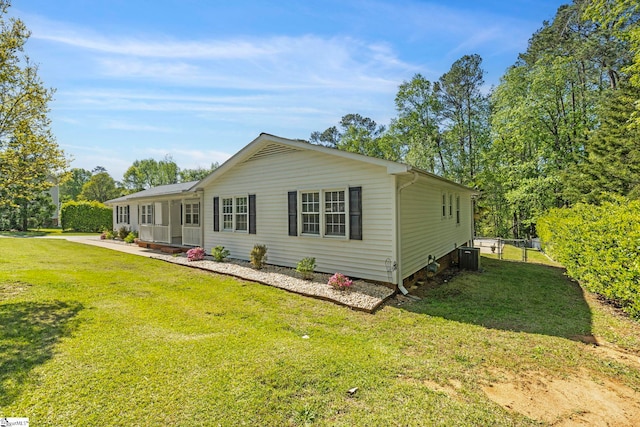 rear view of property with central AC, fence, and a yard