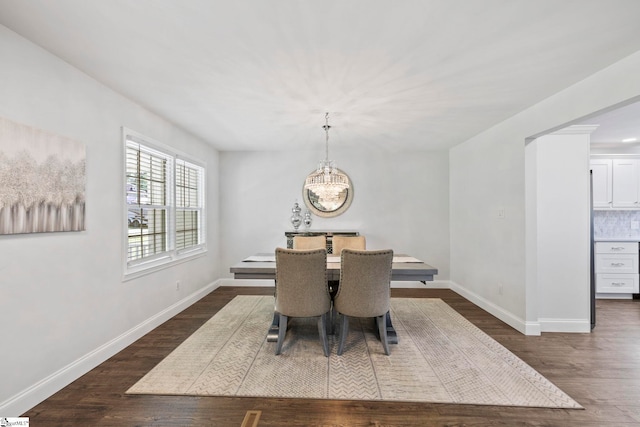 dining space with an inviting chandelier, baseboards, and dark wood-style flooring
