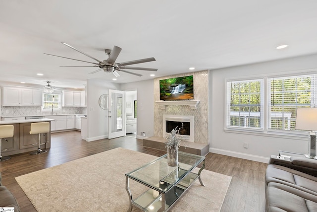 living room featuring a ceiling fan, baseboards, recessed lighting, a high end fireplace, and dark wood-style floors
