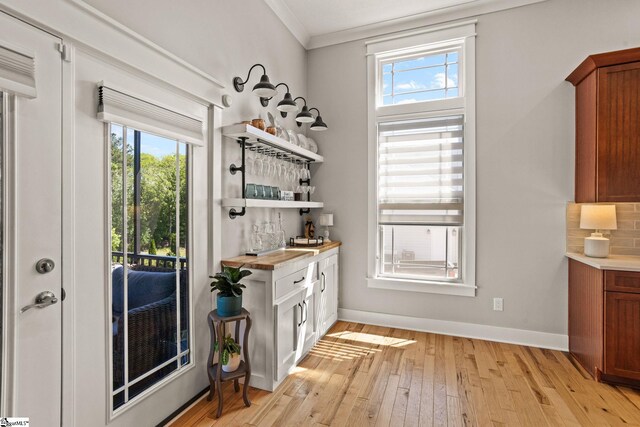 entryway featuring a bar, ornamental molding, baseboards, and light wood-type flooring