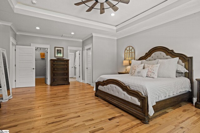 bedroom with visible vents, light wood-type flooring, a raised ceiling, baseboards, and recessed lighting