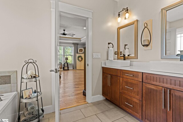 bathroom featuring a ceiling fan, vanity, baseboards, tile patterned floors, and a tray ceiling