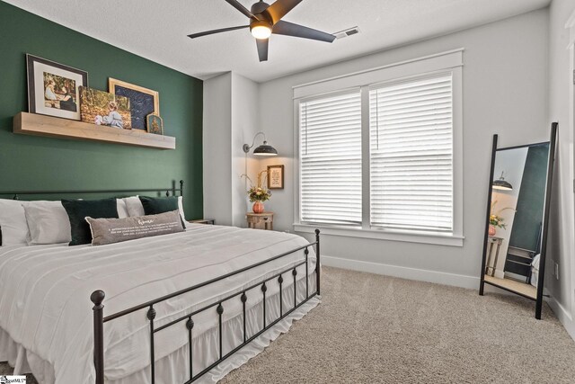 carpeted bedroom with baseboards, a ceiling fan, and visible vents