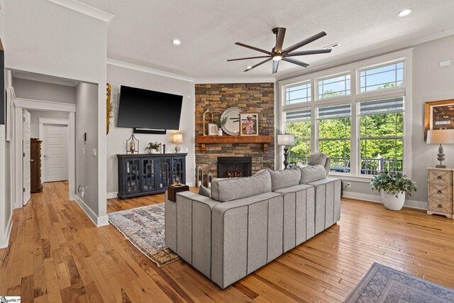 living room with crown molding, baseboards, ceiling fan, and a fireplace