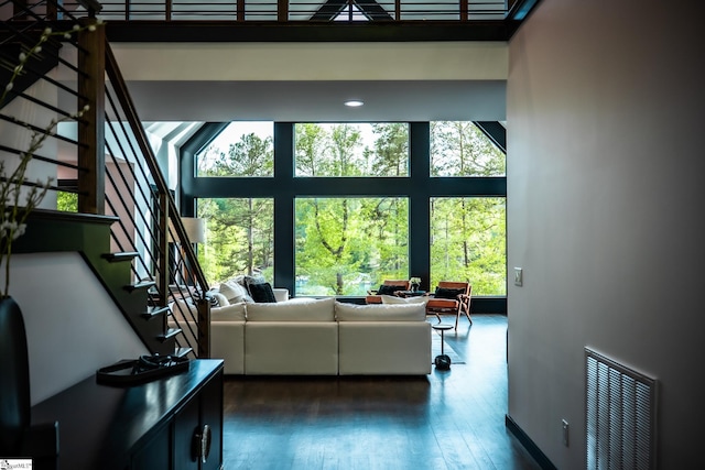 living room with visible vents, dark wood-type flooring, stairs, and a towering ceiling