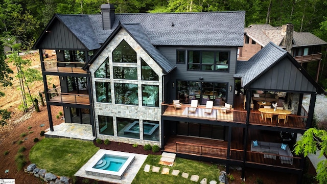 back of property featuring board and batten siding, a balcony, stone siding, and an outdoor hot tub