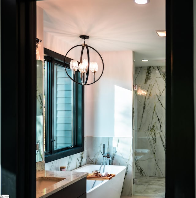 full bath featuring a notable chandelier, vanity, a marble finish shower, recessed lighting, and a soaking tub