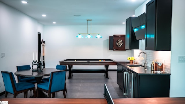 kitchen with dark countertops, a sink, beverage cooler, recessed lighting, and decorative backsplash