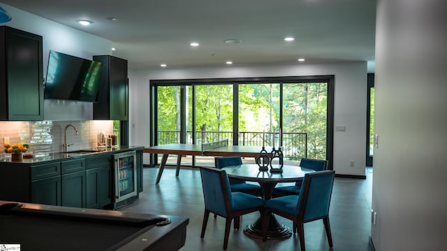 kitchen featuring dark countertops, a sink, beverage cooler, recessed lighting, and tasteful backsplash