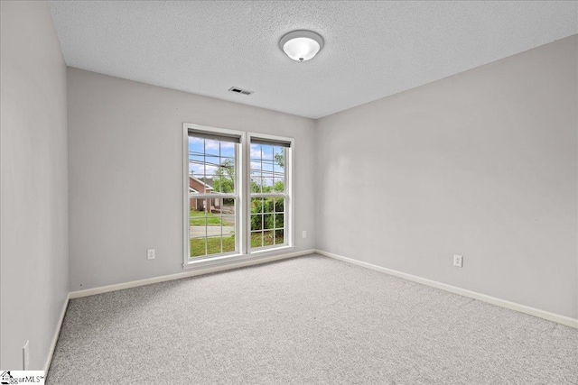 spare room with baseboards, carpet flooring, a textured ceiling, and visible vents