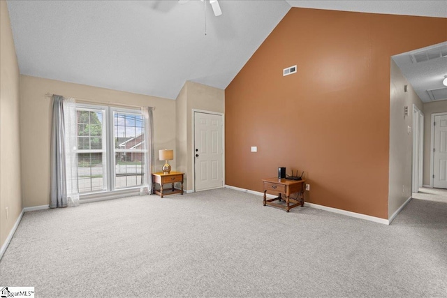 interior space featuring a ceiling fan, visible vents, high vaulted ceiling, baseboards, and carpet