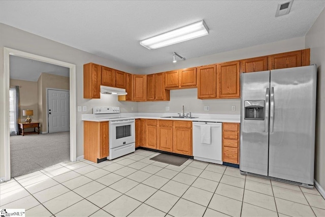kitchen with a sink, light countertops, under cabinet range hood, and white appliances