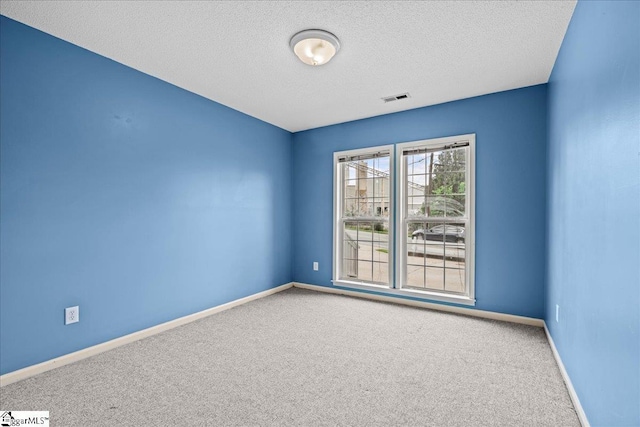 unfurnished room with baseboards, carpet, a textured ceiling, and visible vents