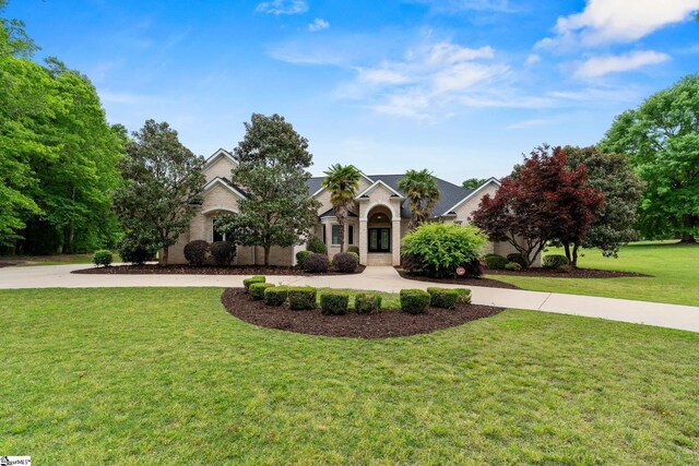 view of front facade featuring curved driveway and a front lawn