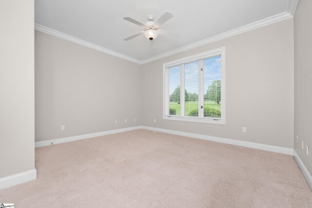 spare room with baseboards, ornamental molding, a ceiling fan, and light carpet