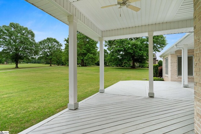 wooden terrace with a lawn and ceiling fan