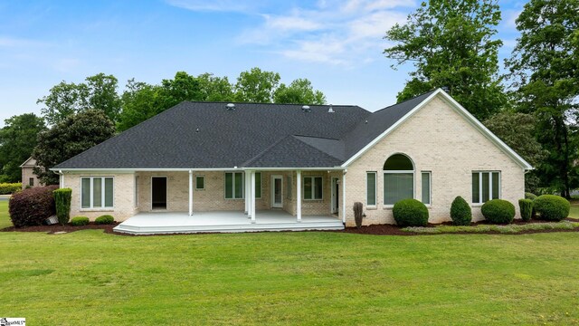 back of property featuring roof with shingles, covered porch, a yard, and brick siding