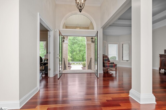 foyer with baseboards, an inviting chandelier, ornamental molding, and plenty of natural light