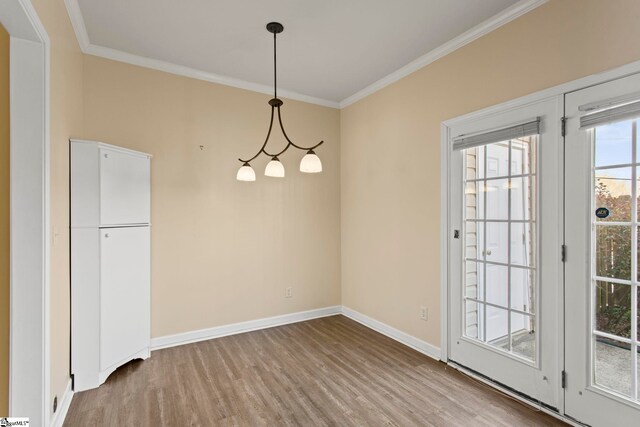 unfurnished dining area with crown molding, baseboards, and wood finished floors