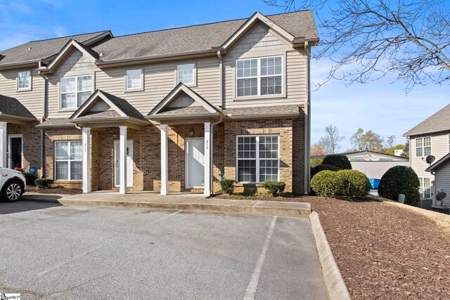 townhome / multi-family property featuring brick siding and roof with shingles